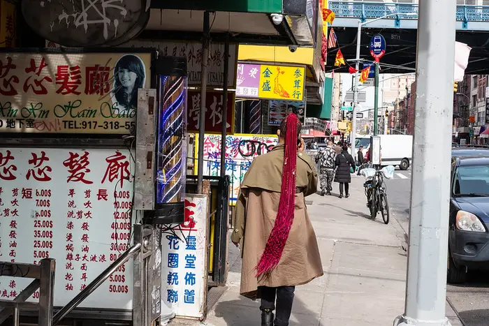 a woman with a long red braid walks through Chinatown
